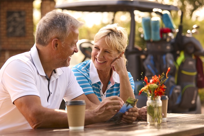 Mature couple enjoying a relaxed conversation over coffee outdoors, representing meaningful connections after 50