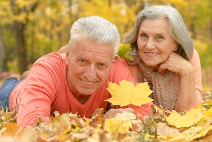 Senior couple smiling together among autumn leaves 