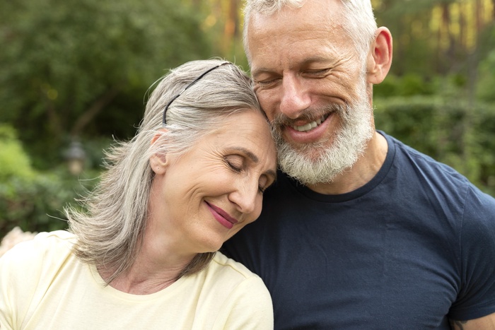 Senior couple smiling and sharing a close moment together outdoors.