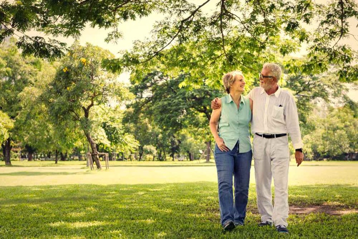 Senior couple walking arm in arm through a green park in Bolton, England
