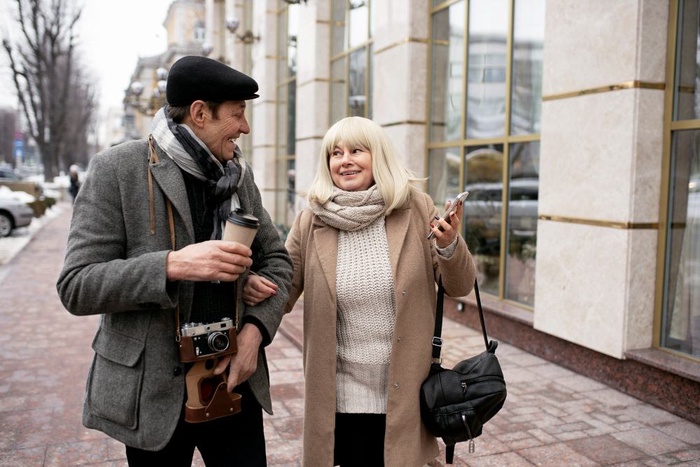 Older couple chatting while walking together along a city sidewalk