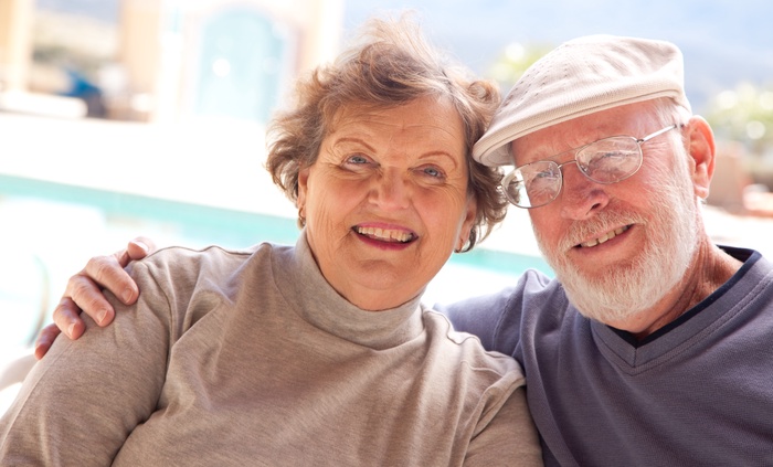 Older couple smiling with their arms around each other outdoors