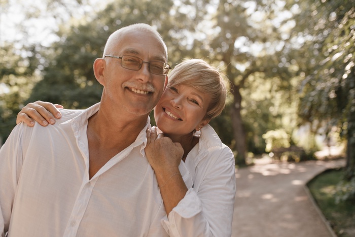 Smiling couple over 50 enjoying time together on a tree-lined walking path