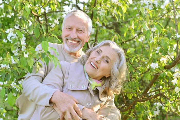 Happy senior couple embracing among flowering trees