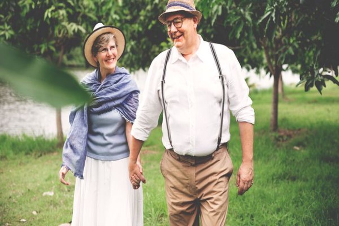 Senior couple holding hands while walking together in a green park