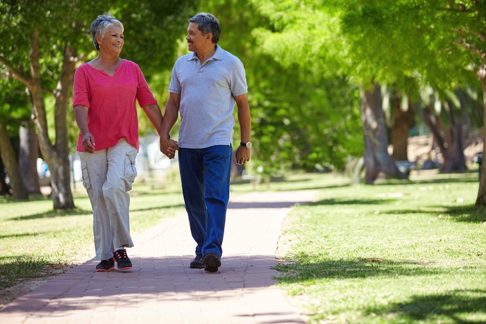 Mature couple walking hand in hand through a leafy park in San Mateo