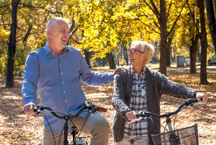 A mature couple enjoying a scenic autumn bicycle ride along a tree-lined trail in Granby