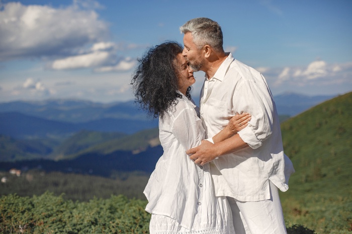 Older couple sharing an affectionate moment outdoors with mountains in the background