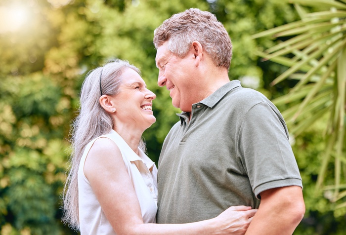 Senior couple over 50 smiling at each other while spending time together outdoors