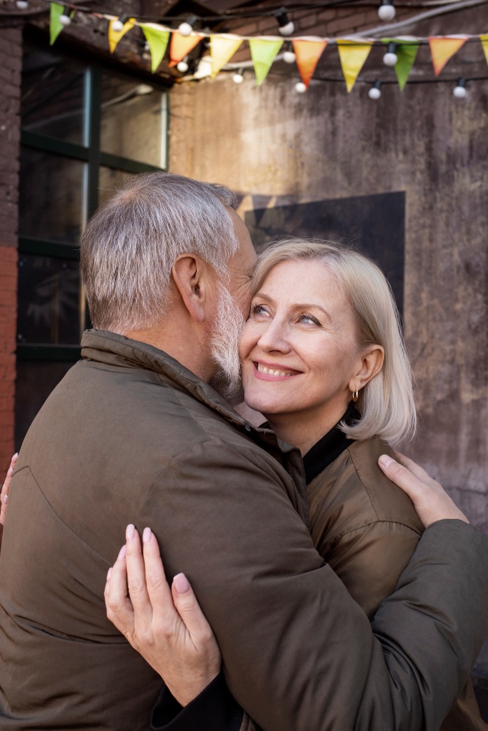 Older couple embracing beneath colorful bunting at a casual public gathering