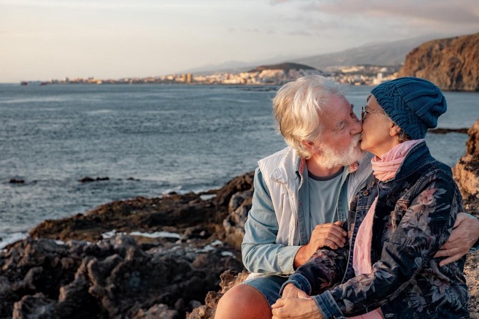 Senior couple sharing a kiss on a rocky coastline during a day trip from Exeter Quayside in Exeter, England