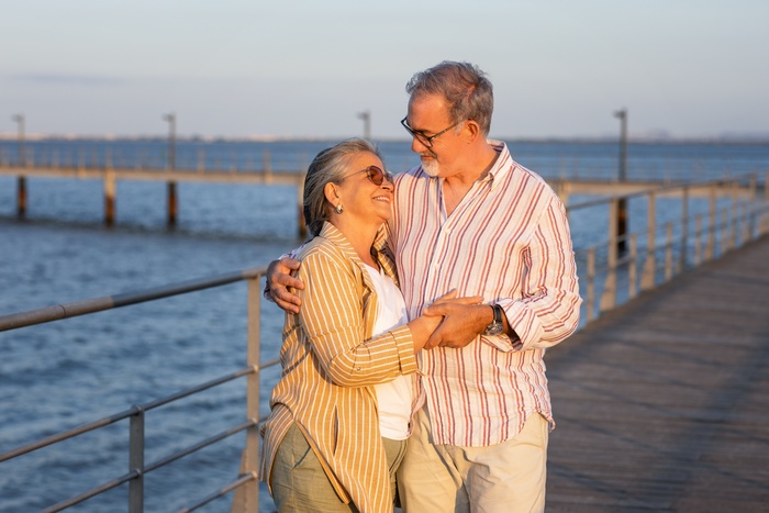 A mature couple enjoys a relaxed walk beside the ocean in Carlsbad, reflecting the warmth, companionship, and active coastal lifestyle shared by local singles over 50.