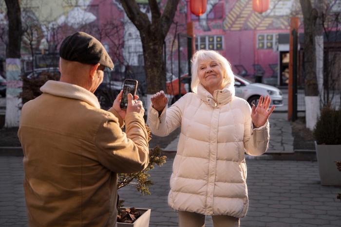 Older man taking a photo of a smiling woman in Sale, England