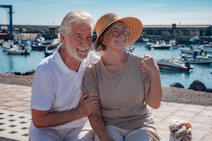 Older couple talking beside a seaside promenade with benches nearby