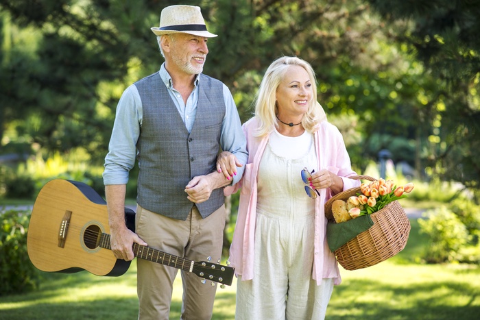Senior couple walking arm in arm with a guitar and picnic basket at Girard Park in Lafayette, Louisiana