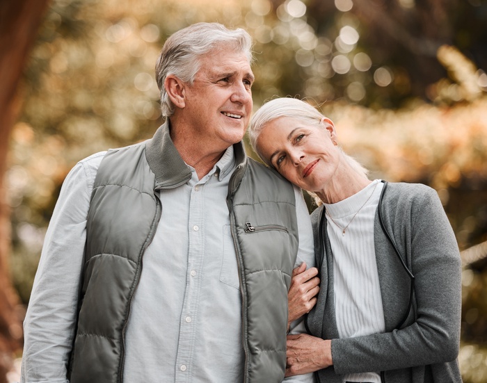 Mature couple smiling together outdoors, sharing a warm moment of connection and companionship.