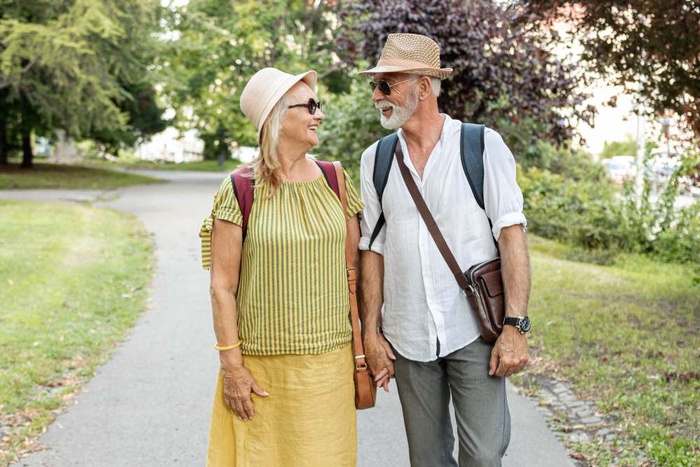 Senior couple holding hands while walking along a sunny park path