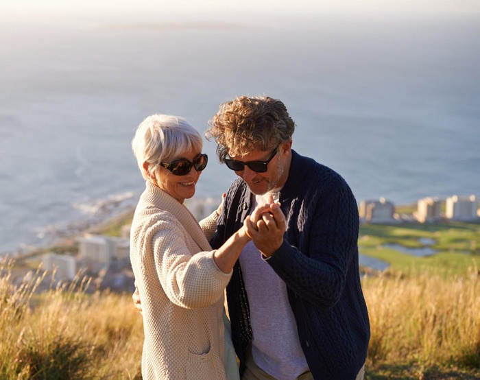 Older adults dancing together on a grassy hillside overlooking the coast in Eastbourne, England