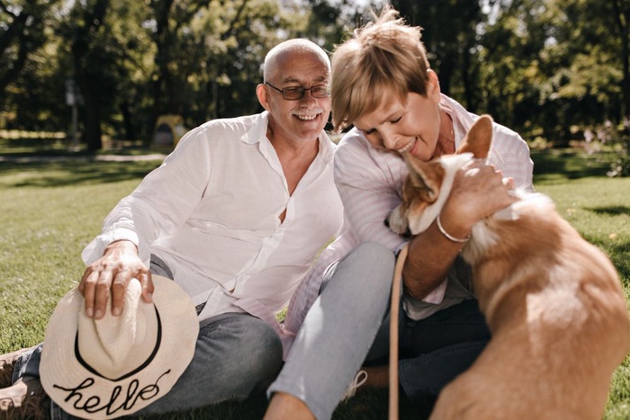 Senior couple relaxing with their dog in a grassy setting near Redbud Park in Abilene, Texas