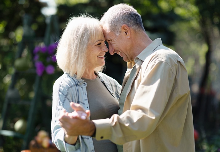 Mature couple smiling together outdoors, sharing a warm moment of connection and companionship.