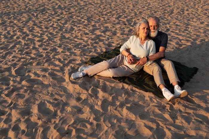 Couple over 50 relaxing together on desert sand