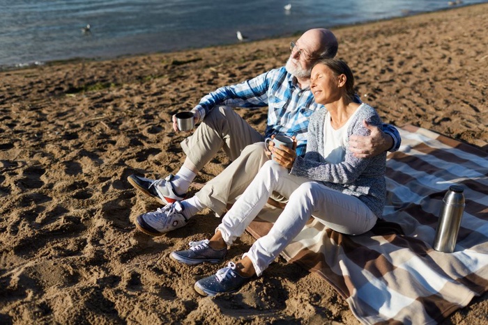 Older couple sitting on a sandy beach