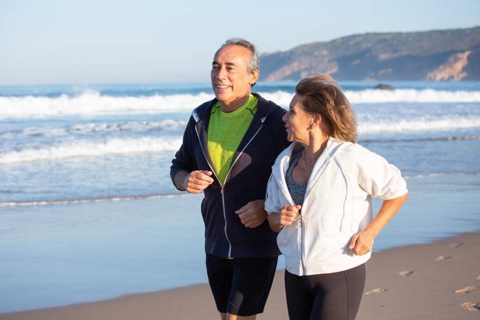 Active mature couple jogging along the beach in South Shields