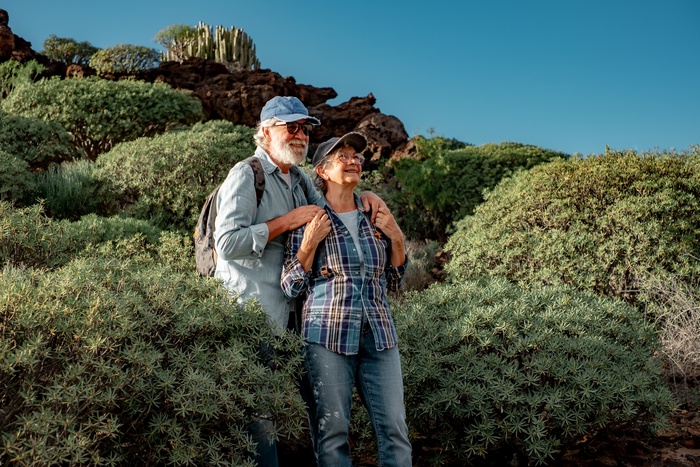 Mature couple walking together along a scenic desert trail, enjoying companionship and the outdoor lifestyle.