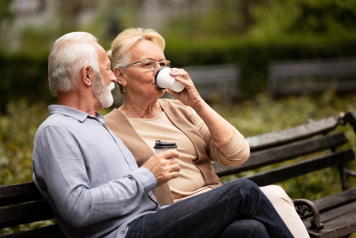 Mature couple with coffee on a park bench