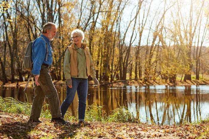 Older couple walking together beside a peaceful riverside in Stratford-upon-Avon
