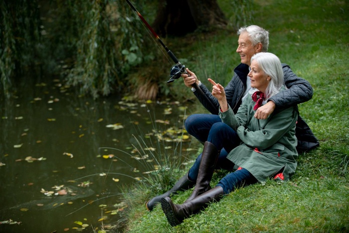 Mature 50+ couple enjoying a relaxed fishing moment beside a lake