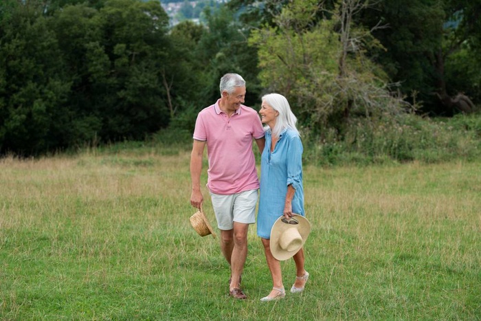 Older couple walking together through a grassy meadow in Trois-Rivières