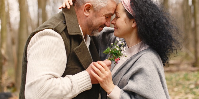 Older couple embracing outdoors in a wooded setting
