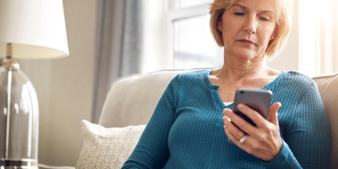 Mature woman thoughtfully reading a message on her phone