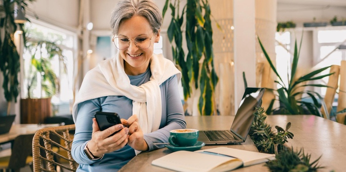 Mature woman exploring online dating at a cafe