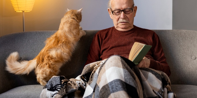 Older man reading beside his cat