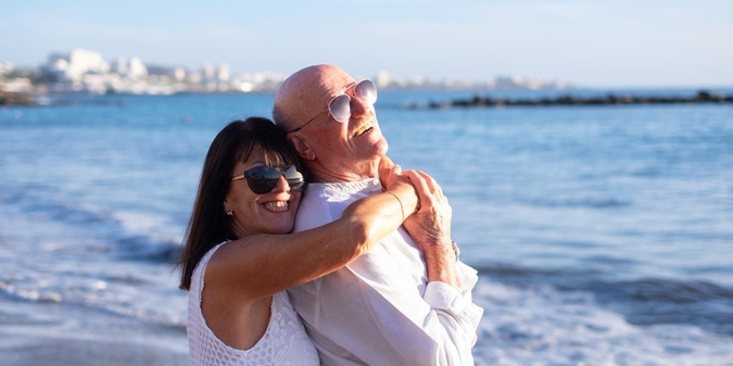 Older couple embracing on a beach by the sea