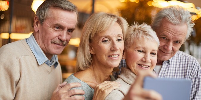 Mature men and women enjoying time together and looking at a smartphone.