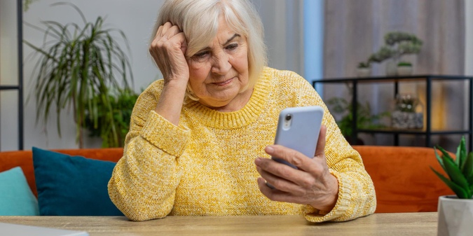 Older woman feeling frustrated while looking at her phone