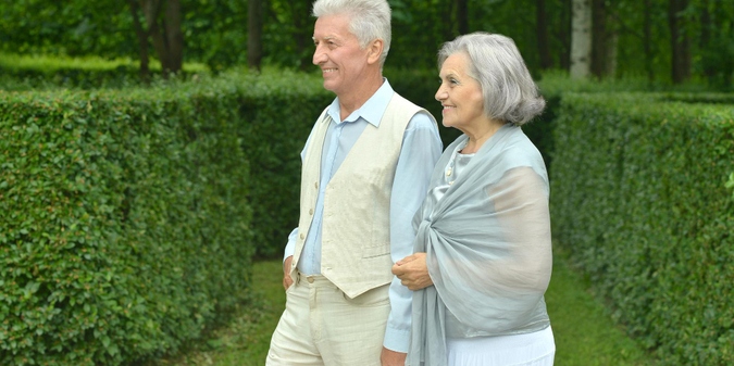 Older couple walking together through a formal garden